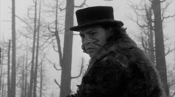 Movie still from “Dead Man” (1995), directed by Jim Jarmusch – A man in a fur coat and a top hat in front of a tree; Close Up shot, Low angle