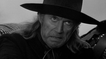Movie still from “Dead Man” (1995), directed by Jim Jarmusch – A man with long hair wearing a black hat; Close Up shot, Over the shoulder angle
