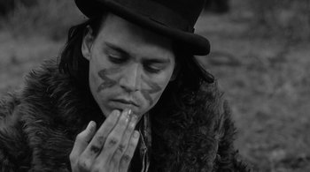 Movie still from “Dead Man” (1995), directed by Jim Jarmusch – A man in a hat and fur coat is praying; Close Up shot, High angle