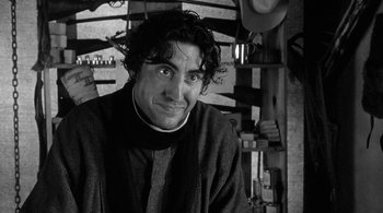 Movie still from “Dead Man” (1995), directed by Jim Jarmusch – Black and white photograph of a man smiling for the camera; Close Up shot, Low angle