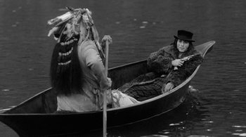 Movie still from “Dead Man” (1995), directed by Jim Jarmusch – Two people in a boat on a body of water; Medium shot, Over the shoulder angle