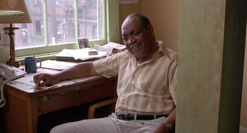 Movie still from “Dead Man Walking” (1995), directed by Tim Robbins – An older man sitting at a desk in front of a window; Medium shot, High angle