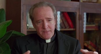 Movie still from “Dead Man Walking” (1995), directed by Tim Robbins – A man wearing a priest's collar and a black suit; Close Up shot, Low angle