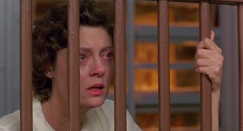 Movie still from “Dead Man Walking” (1995), directed by Tim Robbins – A woman in white shirt behind a metal fence; Close Up shot, High angle