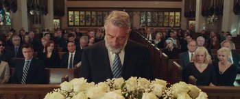 Movie still from “Dirty Grandpa” (2016), directed by Dan Mazer – A man in a suit and tie standing in front of a bunch of flowers; Medium shot, Over the shoulder angle