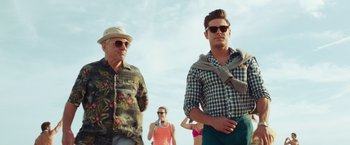 Movie still from “Dirty Grandpa” (2016), directed by Dan Mazer – A man and a woman standing next to each other on the beach; Medium shot, Low angle