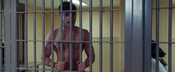 Movie still from “Dirty Grandpa” (2016), directed by Dan Mazer – A shirtless man standing behind bars in a jail cell; Medium shot, Overhead angle