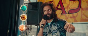 Movie still from “Dirty Grandpa” (2016), directed by Dan Mazer – A man with long hair holding a microphone and smiling; Close Up shot, Over the shoulder angle