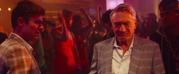 Movie still from “Dirty Grandpa” (2016), directed by Dan Mazer – An older man in a plaid jacket in front of a group of people; Medium shot, Over the shoulder angle
