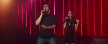 Movie still from “Dirty Grandpa” (2016), directed by Dan Mazer – A man and a woman singing into microphones in front of a red background; Medium shot, Low angle