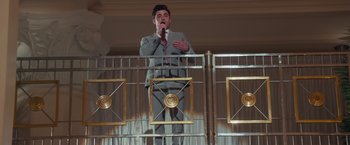 Movie still from “Dirty Grandpa” (2016), directed by Dan Mazer – A man standing on a balcony with a microphone; Medium shot, Low angle