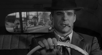 Movie still from “Dead Men Don't Wear Plaid” (1982), directed by Carl Reiner – A black and white photo of a man in a suit and a hat driving; Close Up shot, Over the shoulder angle