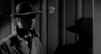 Movie still from “Dead Men Don't Wear Plaid” (1982), directed by Carl Reiner – A black and white photo of a man in a hat and a trench coat; Close Up shot, Over the shoulder angle