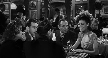 Movie still from “Dead Men Don't Wear Plaid” (1982), directed by Carl Reiner – A black and white photo of people sitting at a table; Medium shot, Over the shoulder angle