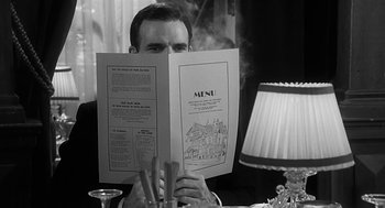 Movie still from “Dead Men Don't Wear Plaid” (1982), directed by Carl Reiner – A man sitting at a table holding a menu in front of his face; Close Up shot, Over the shoulder angle