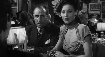 Movie still from “Dead Men Don't Wear Plaid” (1982), directed by Carl Reiner – A man and a woman sitting next to each other holding wine glasses; Medium shot, Low angle