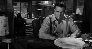 Movie still from “Dead Men Don't Wear Plaid” (1982), directed by Carl Reiner – A black and white photo of a man sitting at a table; Medium shot, Low angle