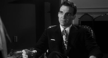 Movie still from “Dead Men Don't Wear Plaid” (1982), directed by Carl Reiner – A black and white photo of a man in a suit and tie holding a glass of wine; Close Up shot, Low angle