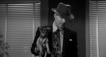Movie still from “Dead Men Don't Wear Plaid” (1982), directed by Carl Reiner – A man in a suit holding a small dog; Close Up shot, Low angle