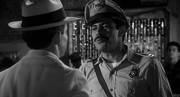 Movie still from “Dead Men Don't Wear Plaid” (1982), directed by Carl Reiner – A man in a police uniform talking to another man in a hat; Close Up shot, Over the shoulder angle