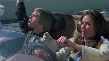 Movie still from “Death Race 2000” (1975), directed by Paul Bartel – A man and a woman sitting in a car; Medium shot, Low angle