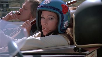Movie still from “Death Race 2000” (1975), directed by Paul Bartel – A woman wearing a helmet while driving a car; Close Up shot, Low angle