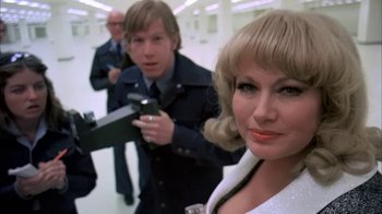 Movie still from “Death Race 2000” (1975), directed by Paul Bartel – A man and a woman holding a gun while another man holds a gun; Close Up shot, Low angle