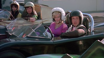 Movie still from “Death Race 2000” (1975), directed by Paul Bartel – A group of people sitting in the back of a car; Medium shot, High angle