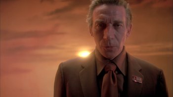 Movie still from “Death Race 2000” (1975), directed by Paul Bartel – A man wearing a suit and tie in front of a sunset; Close Up shot, Low angle