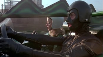 Movie still from “Death Race 2000” (1975), directed by Paul Bartel – A man and a woman in a motorcycle helmet; Medium shot, Low angle
