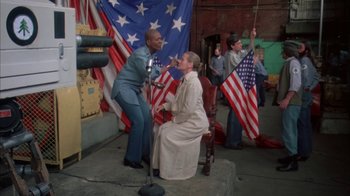 Movie still from “Death Race 2000” (1975), directed by Paul Bartel – A group of people standing next to each other on a stage; Wide shot, High angle