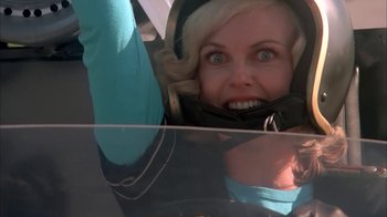 Movie still from “Death Race 2000” (1975), directed by Paul Bartel – A woman in a helmet is hanging upside down in the air; Close Up shot, Low angle
