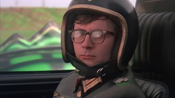 Movie still from “Death Race 2000” (1975), directed by Paul Bartel – A man wearing a helmet and glasses in a car; Close Up shot, Low angle