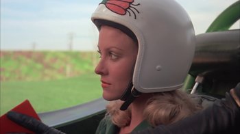 Movie still from “Death Race 2000” (1975), directed by Paul Bartel – A woman wearing a helmet while sitting in a car; Close Up shot, Low angle