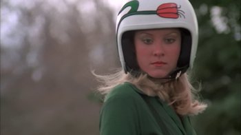 Movie still from “Death Race 2000” (1975), directed by Paul Bartel – A woman wearing a helmet and a green shirt; Close Up shot, Low angle