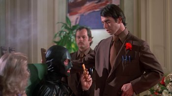 Movie still from “Death Race 2000” (1975), directed by Paul Bartel – A man in a black mask is holding a stick; Medium shot, Over the shoulder angle