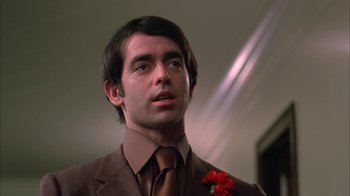 Movie still from “Death Race 2000” (1975), directed by Paul Bartel – A man wearing a brown suit and a brown tie; Close Up shot, Low angle