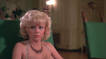 Movie still from “Death Race 2000” (1975), directed by Paul Bartel – A woman with blonde curly hair and a necklace; Close Up shot, High angle