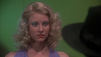 Movie still from “Death Race 2000” (1975), directed by Paul Bartel – A woman in a purple top with makeup on her face; Close Up shot, Low angle