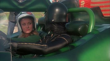 Movie still from “Death Race 2000” (1975), directed by Paul Bartel – A man and a woman are in a green car; Medium shot, Over the shoulder angle