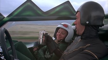 Movie still from “Death Race 2000” (1975), directed by Paul Bartel – A man and a woman sitting in the back of an airplane; Medium shot, Low angle