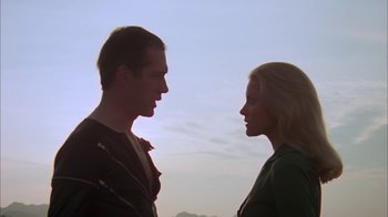 Movie still from “Death Race 2000” (1975), directed by Paul Bartel – A man and a woman face to face in front of a sky background; Close Up shot, Low angle