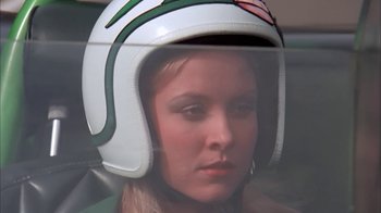Movie still from “Death Race 2000” (1975), directed by Paul Bartel – A woman wearing a motorcycle helmet sitting in a car; Close Up shot, Low angle