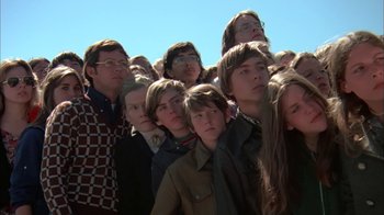 Movie still from “Death Race 2000” (1975), directed by Paul Bartel – A group of people that are standing in a crowd; Medium shot, High angle