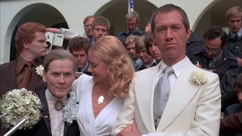 Movie still from “Death Race 2000” (1975), directed by Paul Bartel – A man and a woman in a white suit and tie; Close Up shot, Low angle