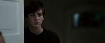 Movie still from “Death Sentence” (2007), directed by James Wan – A young man in a black t - shirt is looking at the camera; Close Up shot, Over the shoulder angle