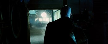Movie still from “Death Sentence” (2007), directed by James Wan – A man in a black jacket is looking at a building; Wide shot, Over the shoulder angle