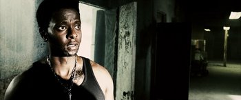 Movie still from “Death Sentence” (2007), directed by James Wan – A man in a black tank top is standing in a dark room; Close Up shot, Low angle