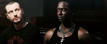 Movie still from “Death Sentence” (2007), directed by James Wan – A man wearing a black tank top and a cross necklace; Close Up shot, Over the shoulder angle
