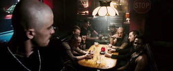 Movie still from “Death Sentence” (2007), directed by James Wan – A group of men sitting at a wooden table; Wide shot, High angle